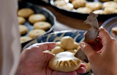 a person holding a piece of food in front of some other plates with cookies on them