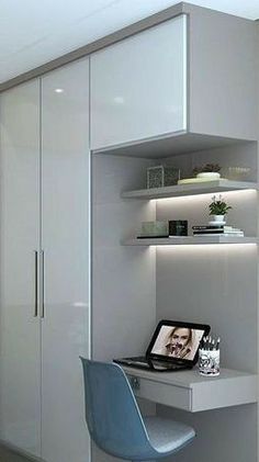 a desk with a laptop on top of it in front of a book shelf and closet