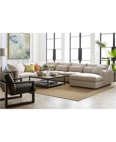 a living room filled with lots of furniture next to tall windows and potted plants