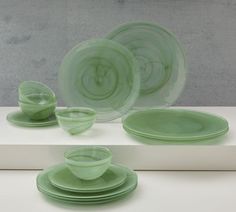 green glass dishes and cups sitting on top of a white countertop next to each other