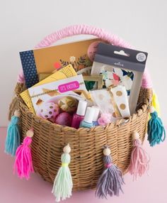 a wicker basket filled with lots of crafting supplies and crafts on top of a pink table