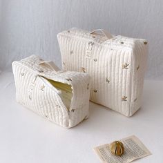 two white suitcases sitting next to each other on top of a table with an open book