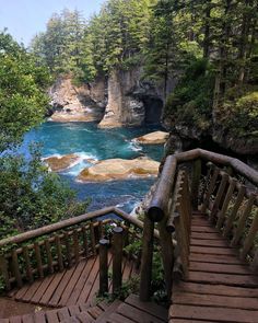 stairs lead down to the blue water and rocky cliffs in the distance, with trees on either side