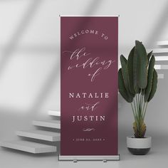 a welcome sign next to a potted plant on a table with stairs in the background