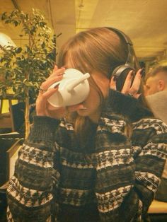 a woman wearing headphones and holding a cup