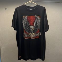 a harley davidson t - shirt hanging on a hanger next to a white wall