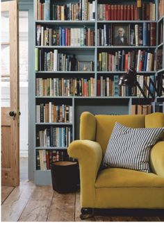 a yellow chair sitting in front of a book shelf filled with books