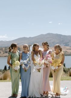 a group of women standing next to each other in front of a lake and mountains