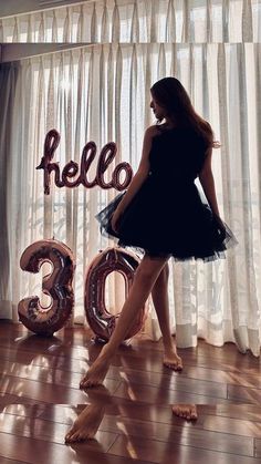 a woman standing in front of a window with the number 30 on it and balloons