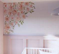 a baby's room with pink flowers painted on the wall and white crib