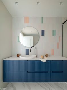 a bathroom with blue cabinets and a round mirror