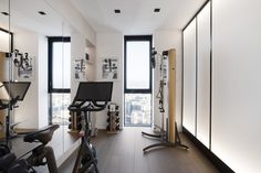 an exercise room with mirrors and treadmills on the wall, along with large windows