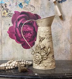 a vase sitting on top of a table next to a beaded necklace and flower