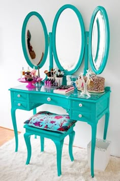 a blue vanity with three mirrors and a stool