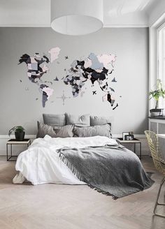 a bedroom with grey walls and white bedding has a large map on the wall