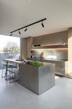 an open kitchen with stainless steel appliances and counter tops, along with bar stools