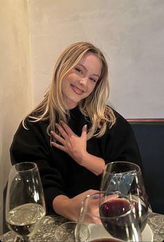 a woman sitting at a table with two wine glasses