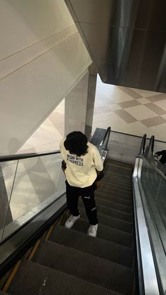 a person riding an escalator with their back to the camera and looking down