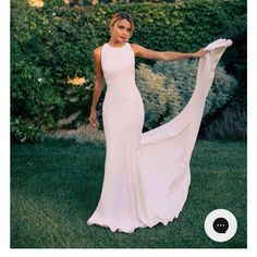 a woman in a long white dress is holding up a piece of cloth and posing for the camera