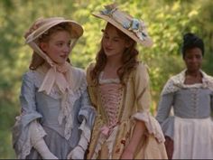 two girls in dresses and hats standing next to each other