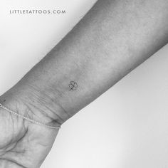 a person's wrist with a small clover tattoo on the left side of their arm