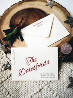 two white envelopes sitting on top of a wooden table next to a christmas tree