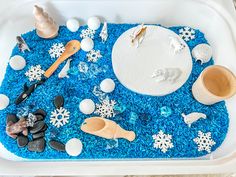 a tray filled with blue and white snowflakes next to wooden spoons, salt and pepper shakers