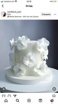 a white cake with flowers on it sitting on top of a table in front of an instagram page