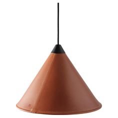 a brown leather lamp shade hanging from a black metal hook on an isolated white background