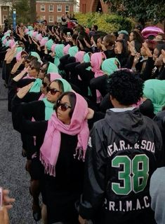 a large group of people wearing pink and green scarfs are lined up on the street