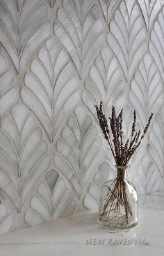 a vase filled with dried lavender sitting on top of a white marble counter next to a wall