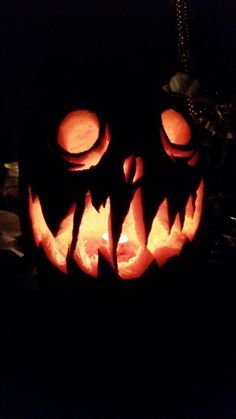 a carved pumpkin with glowing eyes and teeth on it's face in the dark