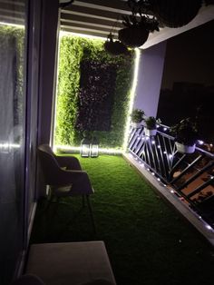 an outdoor area with artificial grass and plants on the walls, along with chairs and tables