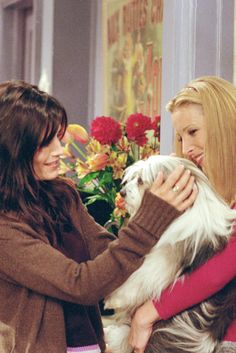 two women petting a small white dog