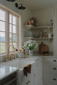 a kitchen with white cabinets and gold faucets in the window sill above the sink