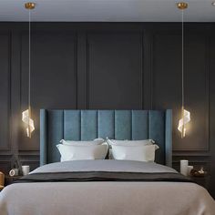 a bed with two lamps hanging from the ceiling above it and a blue headboard