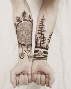 two people with tattoos on their arms holding each other's hands in front of the camera