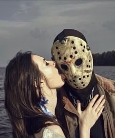 a woman kissing a man wearing a mask