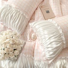 a bouquet of white roses sitting on top of a bed next to pillows and sheets