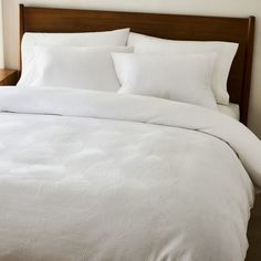 a bed with white sheets and pillows in a room