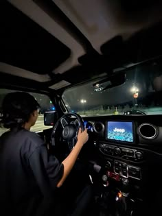 a woman driving a car at night with her hands on the steering wheel and dashboard