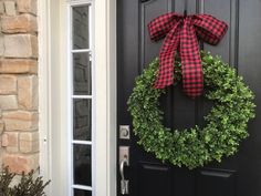 a black door with a red and black wreath hanging on it's front door