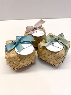 three small baskets with tags and bows on them