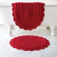 two red rugs sitting next to each other on the floor in front of a bathtub