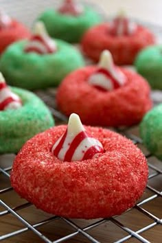 red and green donuts with candy canes on them sitting on a cooling rack