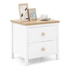 a white nightstand with two pictures on it and a coffee cup next to the drawer