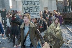 a group of people walking down a street with signs in the air and one person holding a sign