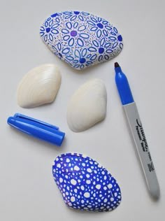 some rocks and markers are laying next to each other on a white surface with blue designs