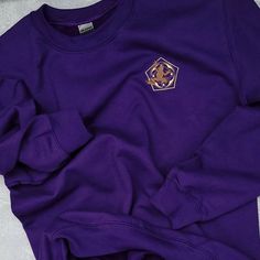 a purple sweatshirt with a gold emblem on it