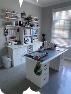 a sewing machine sitting on top of a white desk in a room with lots of shelves